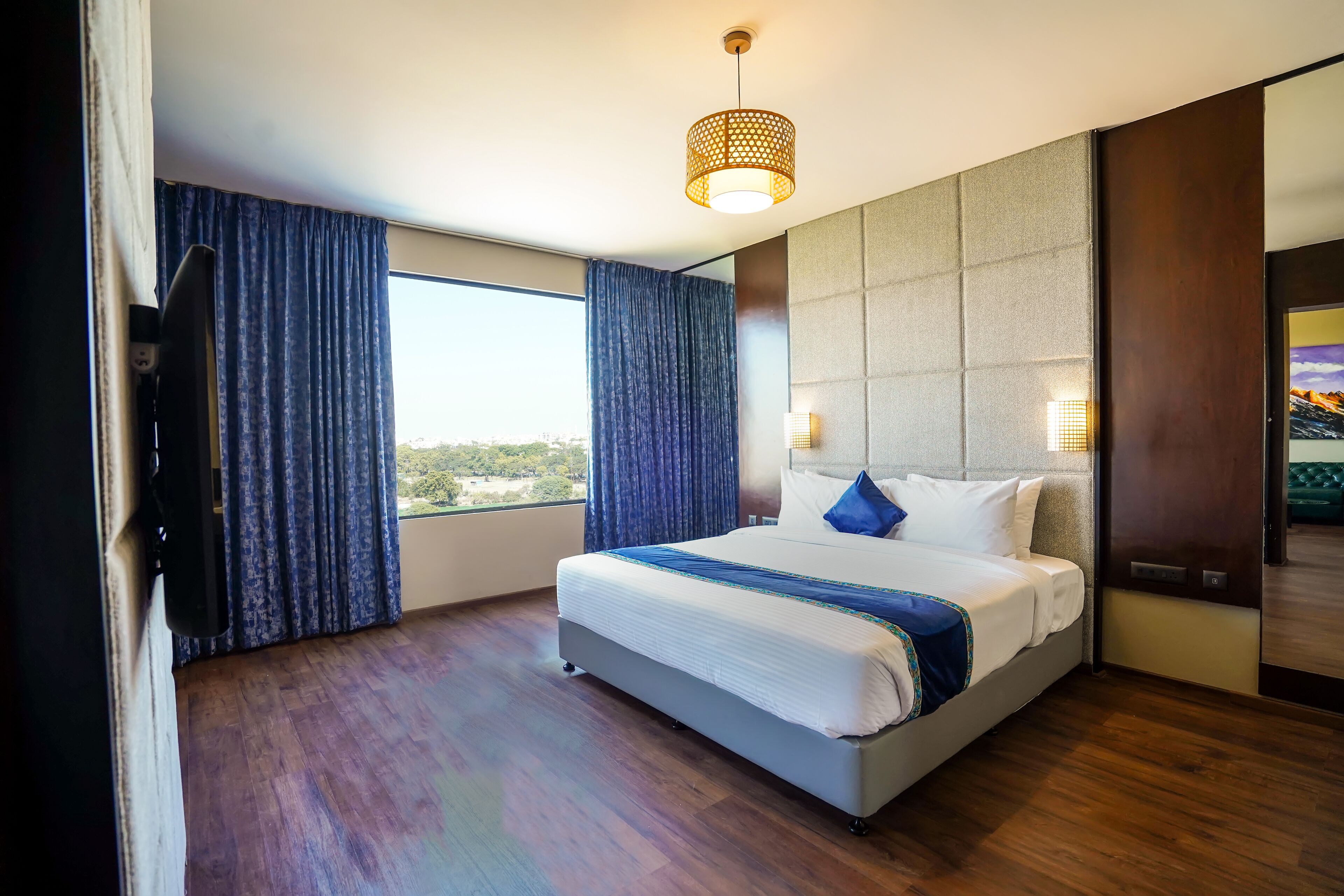 Una habitación de hotel moderna con una cama grande, vistas de la ciudad y un ventanal amplio.