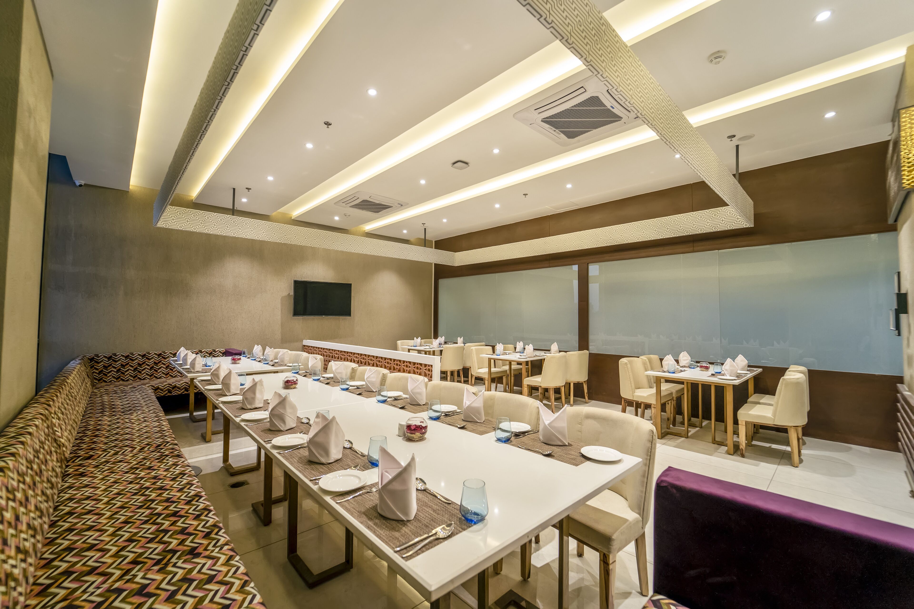 A conference room with long tables, chairs, and a patterned bench.