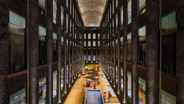 A modern building with a central atrium, multiple floors, and a pool area. - Essentia Luxury Hotel Indore (Indore)
