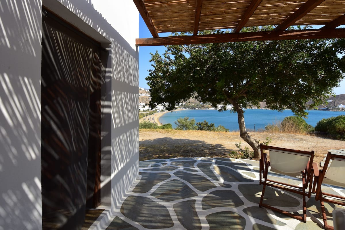 A patio with a stone floor and a view of the sea.