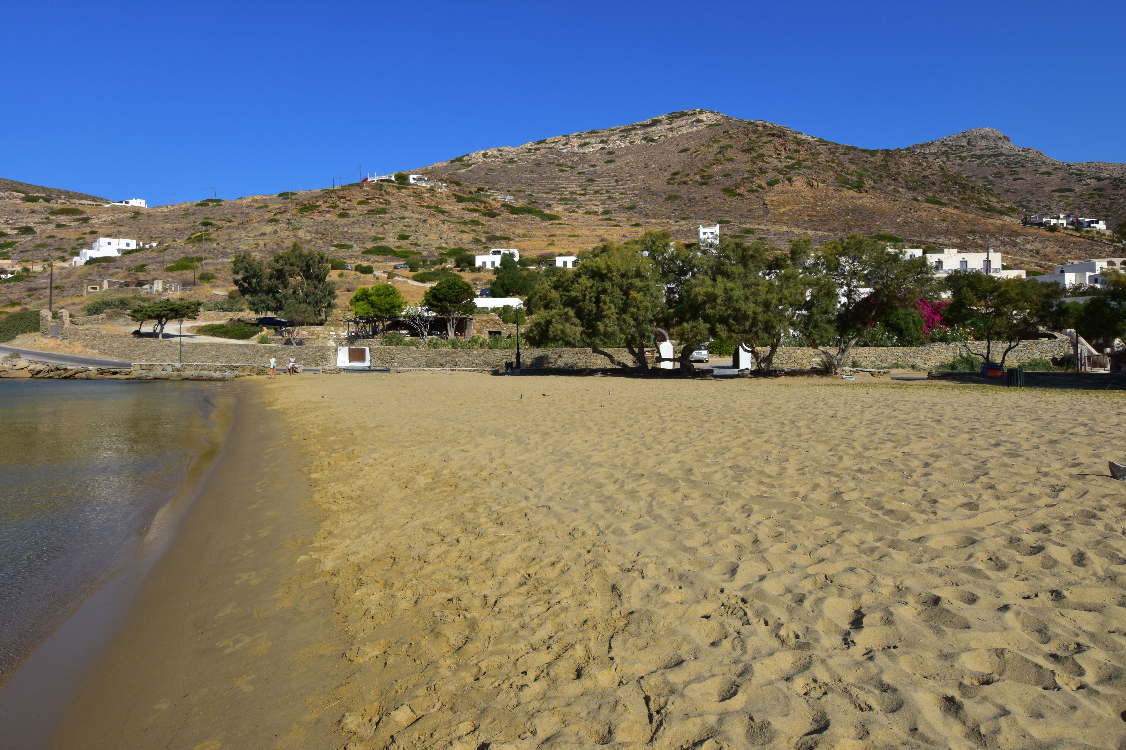 Une plage de sable avec des bâtiments blancs et une colline en arrière-plan.