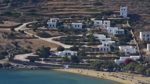 A coastal village with white buildings, a beach, and a clear view of the sea. - Petra Holiday Village (Ios)
