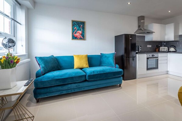 A modern kitchen with a black refrigerator, white cabinets, and a tiled floor.