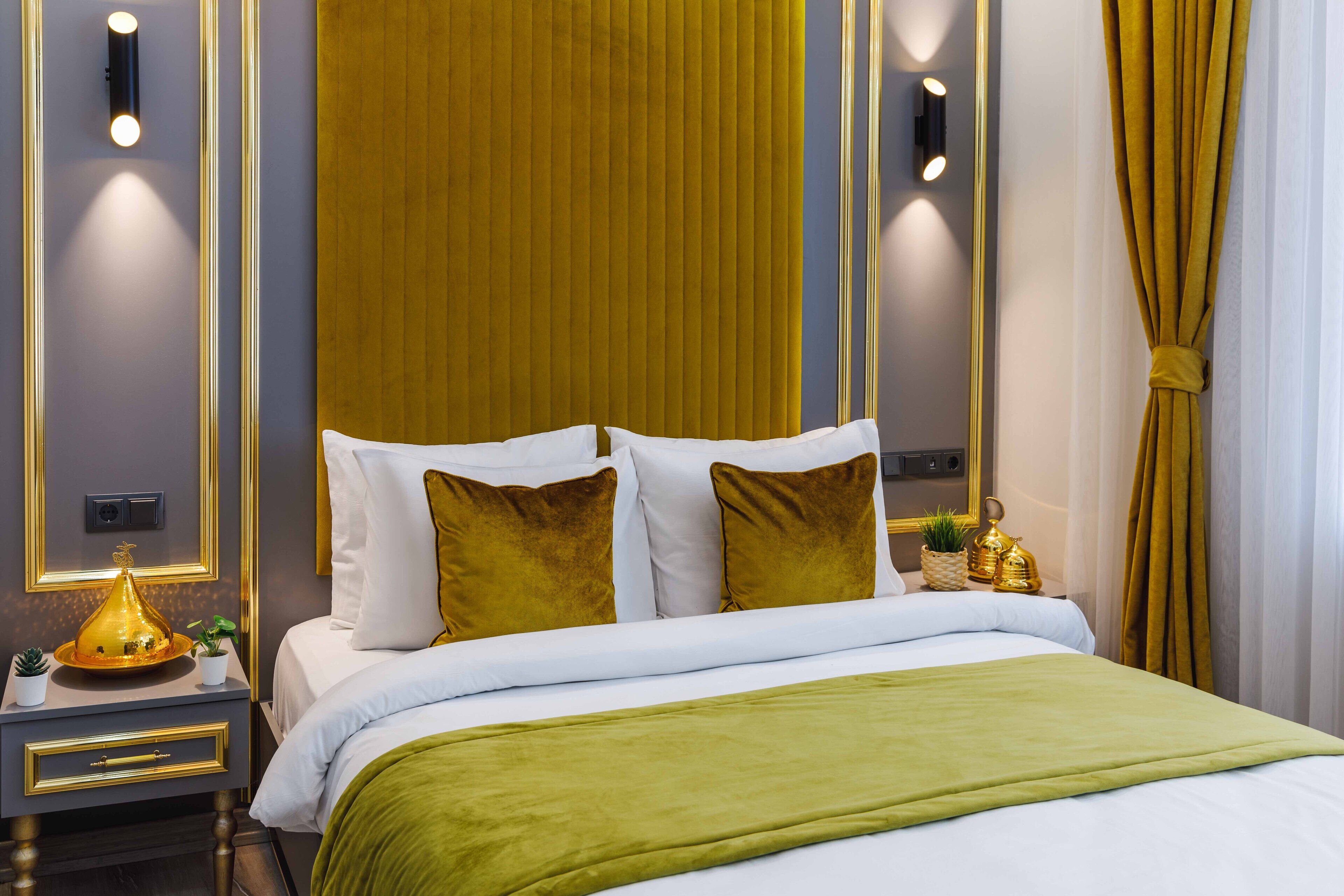 A modern hotel room with a neatly made bed, a bedside table with a lamp, and a decorative wall panel.