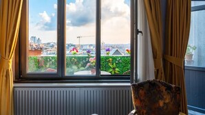 Ein Zimmer mit Blick auf eine Stadtlandschaft, ein Fenster mit Vorhängen und eine Heizung.