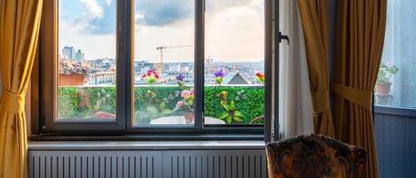 Una habitación con vistas a un paisaje urbano, una ventana con cortinas y un radiador.