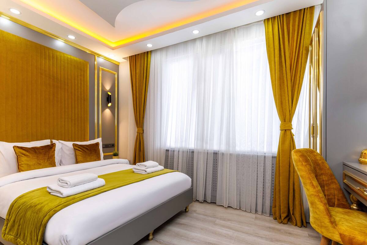 A hotel room with a large bed, a desk, and a chair.