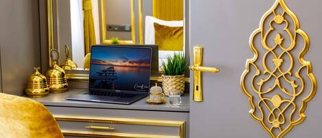 A modern desk with a laptop, gold accents, and a decorative wall piece.