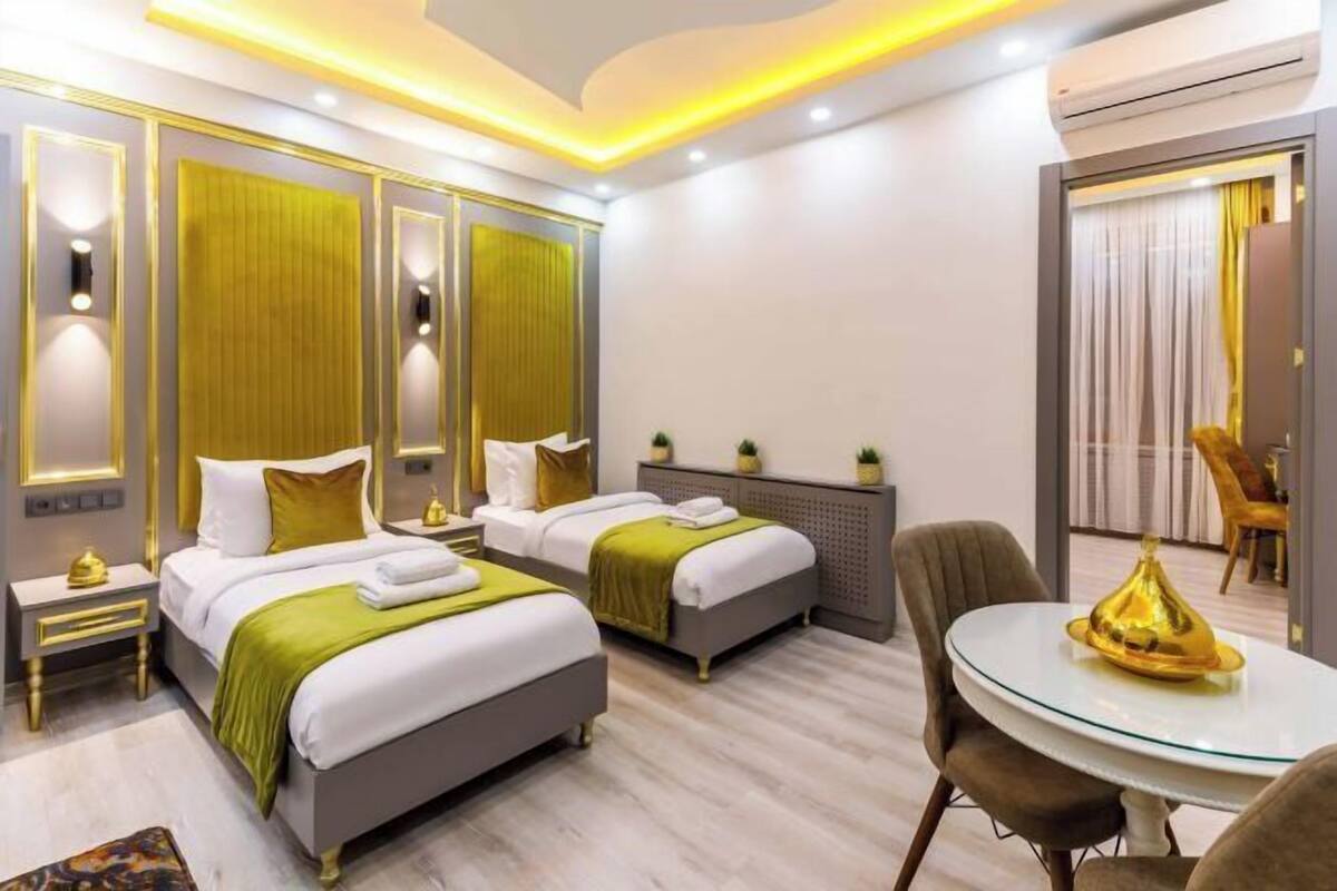 A hotel room with two beds, a round dining table, and a mirror.