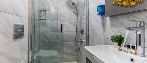 A modern bathroom with a glass-enclosed shower, a white toilet, and a vanity with a sink and mirror.
