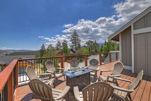 A deck with outdoor furniture and a fire pit, overlooking a mountainous landscape.