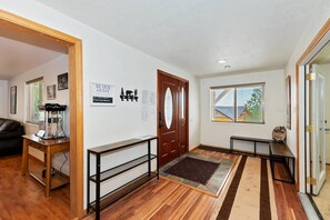 A hallway with a wooden bench, a door with a glass panel, and a welcome sign.