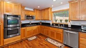 A modern kitchen with wooden cabinets, stainless steel appliances, and a window with a view of the outdoors.