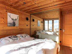 A wooden cabin room with a bed, a mirror, and a window with a snowy view. - Val Thorens: Stunning apt for 8, close to slopes and shops (Val Thorens)