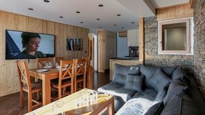 Una sala moderna con una mesa de comedor de madera, un sofá gris y una pared de acento de piedra.