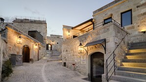 Un edificio de piedra con una escalera que lleva a un segundo piso, un letrero que indica un comedor para desayunos y un letrero que anuncia una cueva.