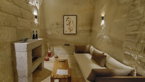 Una habitación con paredes de piedra, una mesa de centro de madera, un sofá y una chimenea decorada con objetos.