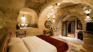 Un dormitorio acogedor con paredes de piedra, una cama de madera, un banco con cojines y un espejo en la pared.