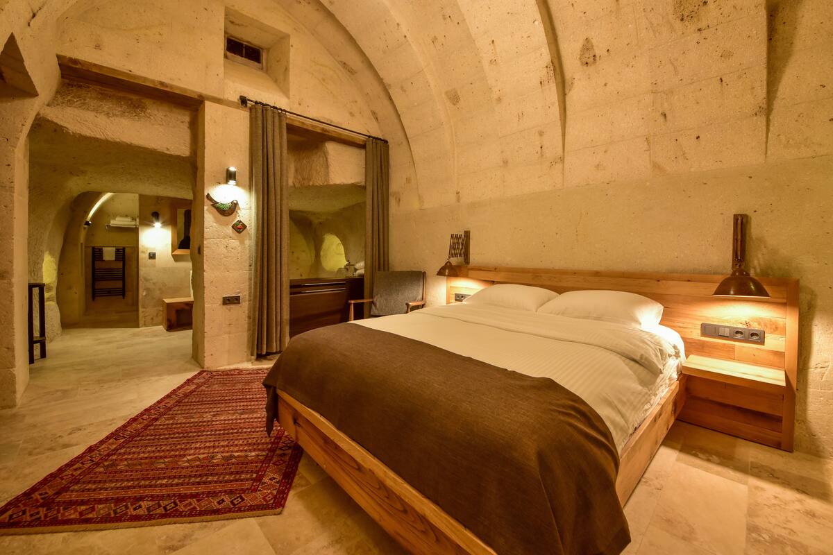 A bedroom with a wooden bed, a nightstand, a lamp, and a red carpet.