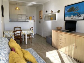 Ein kompakter Wohnbereich mit Essplatz, einer Couch, einem Fernseher und einem Schrank.