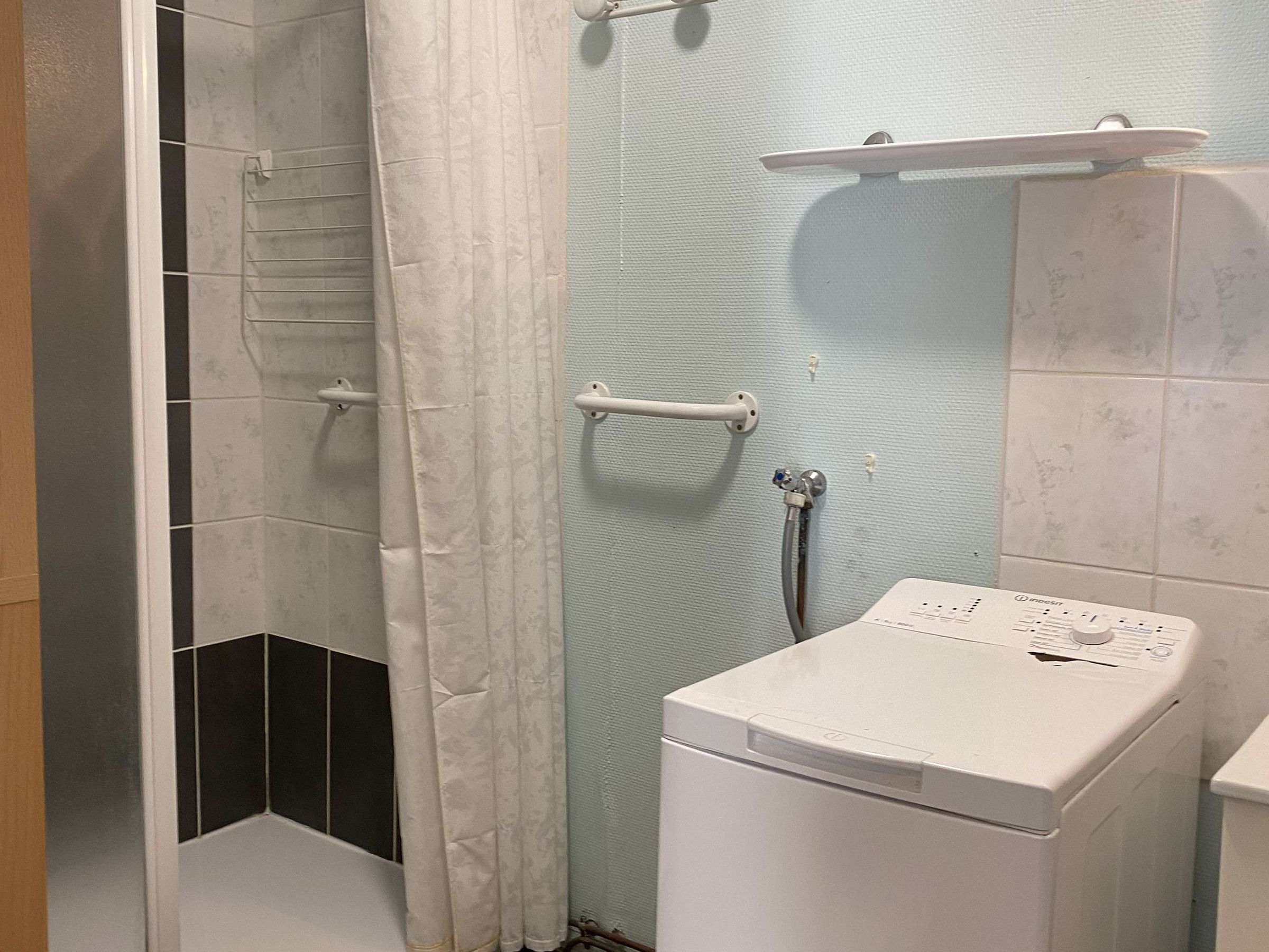 Un baño con ducha, inodoro y lavadora.