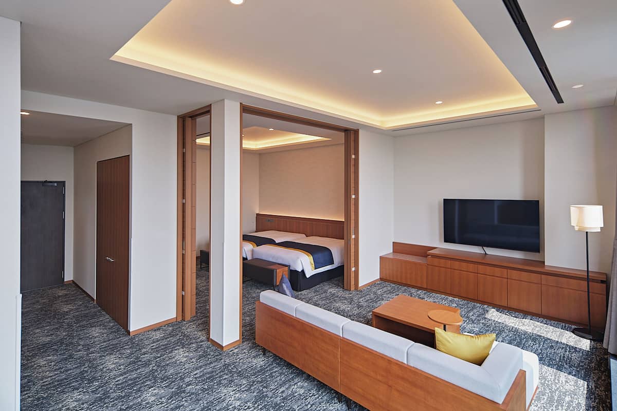 Une chambre d’hôtel moderne équipée d’un canapé, d’un lit, d’une télévision et d’un bureau.