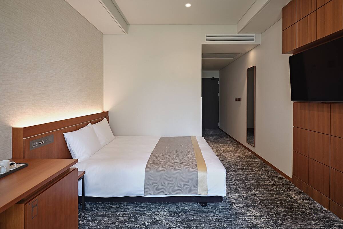 Une chambre d’hôtel équipée d’un lit, d’un bureau, d’une télévision à écran plat et d’un système de climatisation.