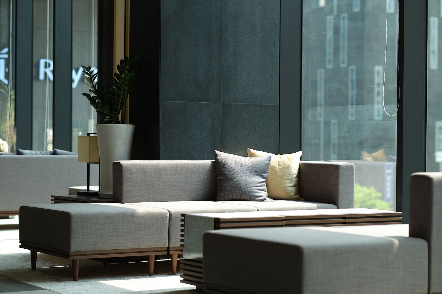 A modern living room with a sofa set, a side table, and a potted plant.