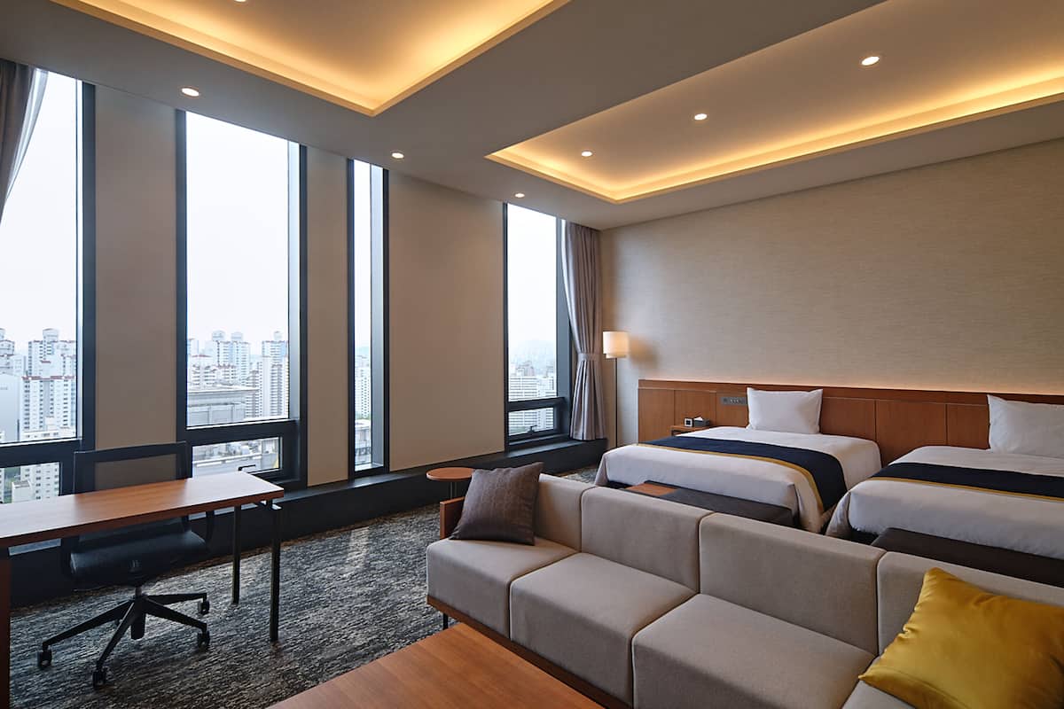 Une chambre d’hôtel avec un grand lit, un canapé, un bureau et une vue sur la ville.