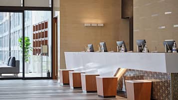Un área de recepción con diseño moderno, que incluye un mostrador de recepción, un espacio de estar y un amplio ventanal con vistas a la ciudad.