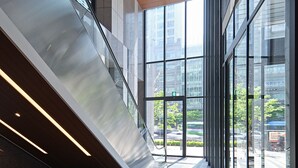 A modern interior with a glass elevator shaft, a large window offering a view of the outside, and a ceiling with recessed lighting. - Roynet Hotel Seoul Mapo (Seoul)