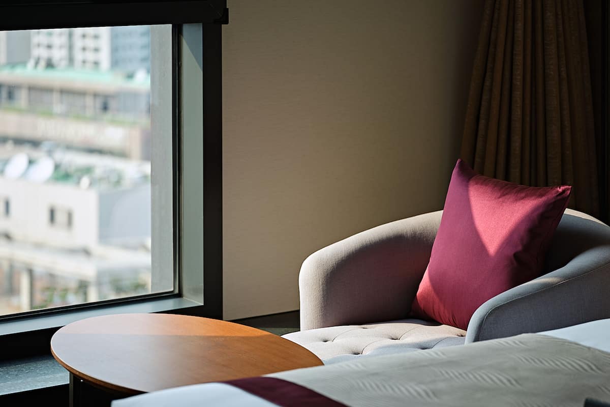 Une chambre d’hôtel avec un lit, une petite table ronde et une fenêtre donnant sur la ville.