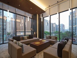Una sala de estar moderna con un sofá modular, una mesa de centro y grandes ventanales que ofrecen vistas a la ciudad.