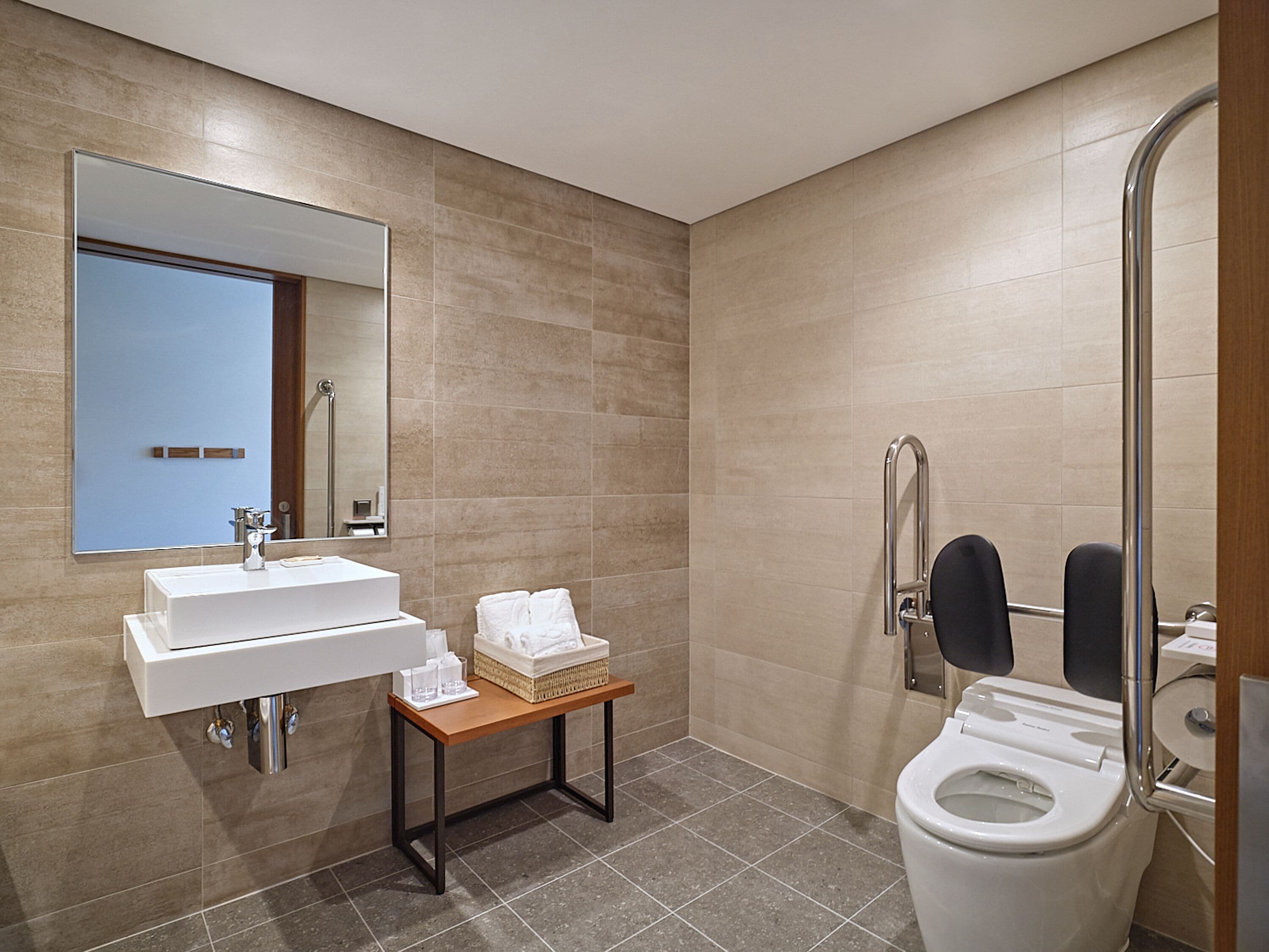 Un baño moderno con lavamanos, espejo y retrete.