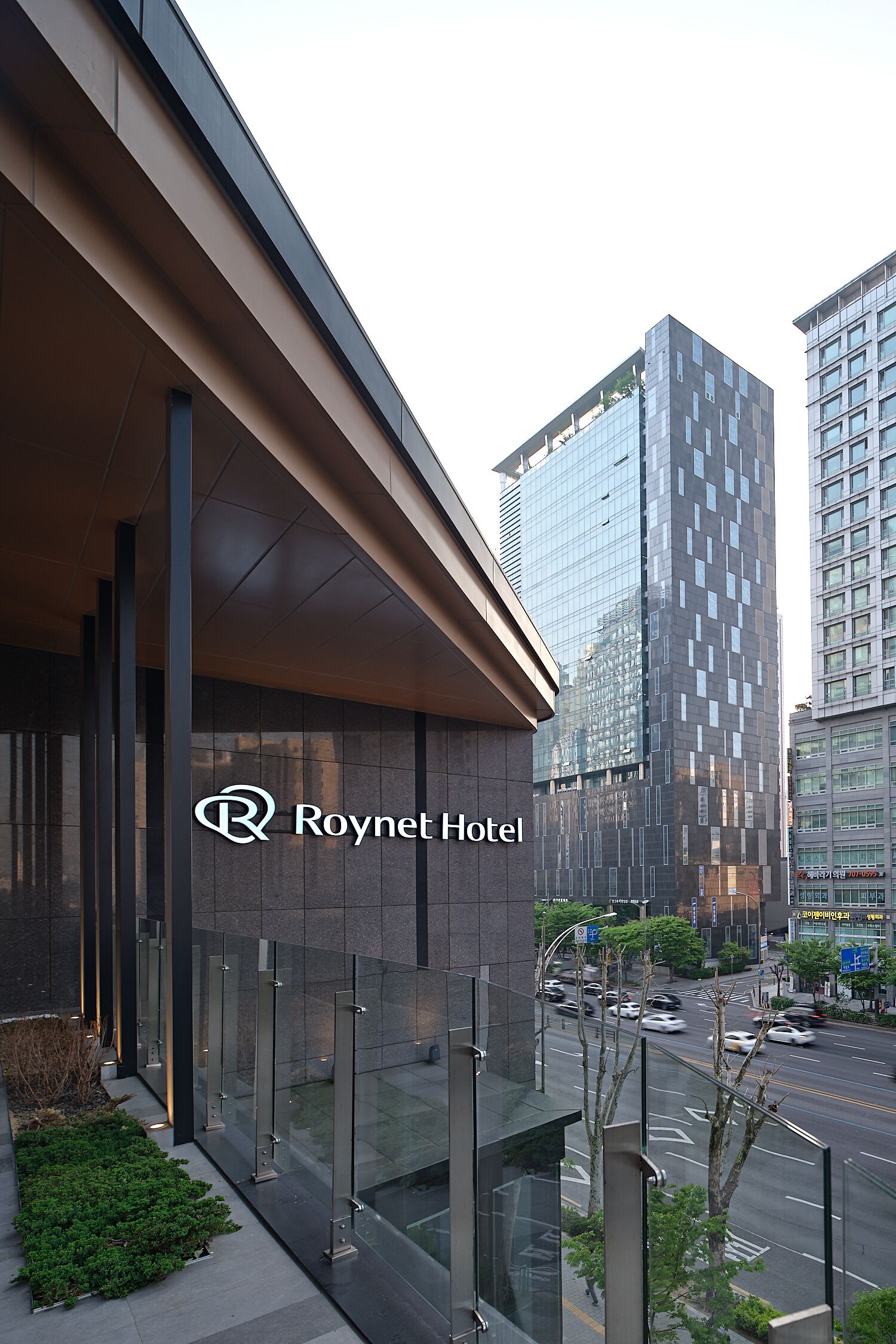 A modern hotel building with a glass facade and a logo.