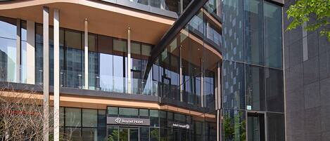 Un hotel moderno con fachada de vidrio, techo curvo y un letrero que dice "Roynet Hotel".