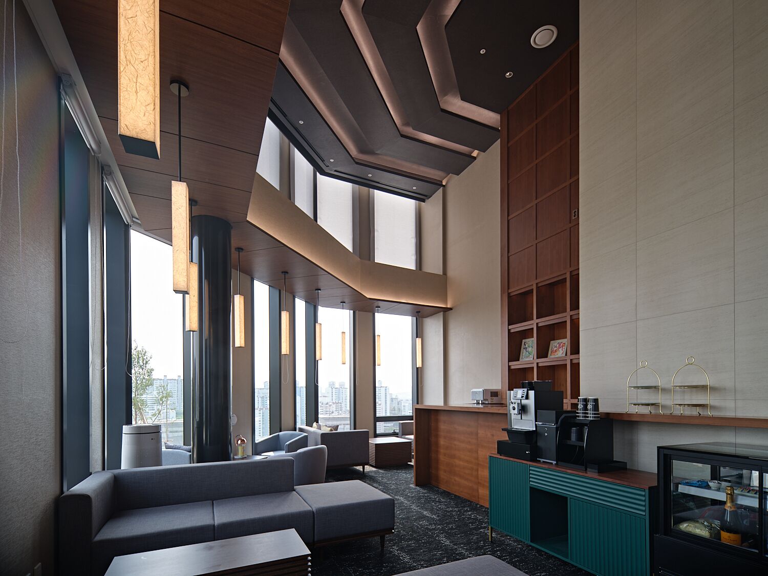 A modern lounge area with seating, a coffee station, and a view of the city.