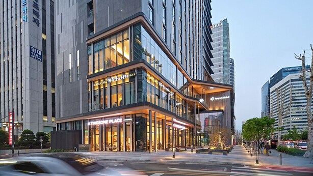 Un edificio moderno con fachada de vidrio, letrero de Korean Grill y un letrero de Holiday Inn Express.