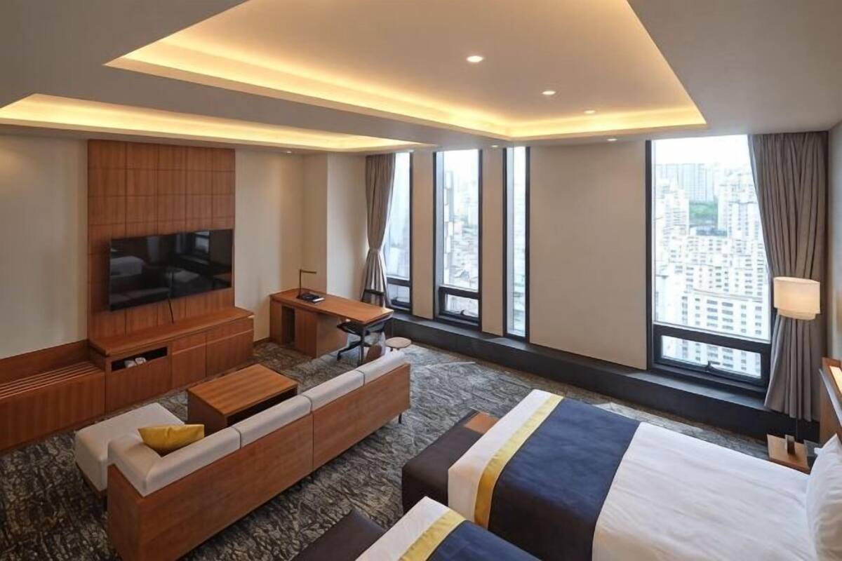 Une chambre d’hôtel avec un grand lit, un canapé, une télévision et un bureau.