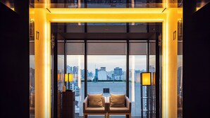 Habitación de hotel moderna con vistas a la ciudad, que incluye un sofá y dos lámparas.