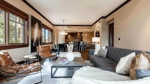 Een ruime woonkamer met een bank, fauteuils en een salontafel. Achterin is een eethoek met een tafel en stoelen.