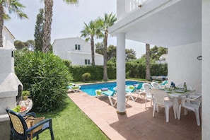 Un espace aménagé au bord de la piscine, comprenant une piscine, des chaises longues et une table dressée pour les repas.
