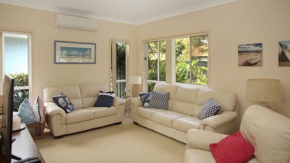 A living room with two beige sofas, a television, and a wicker basket.