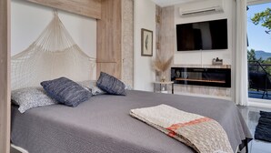 Quarto moderno com uma cama grande, televisão e vista para o exterior.
