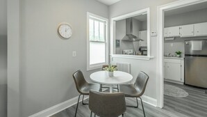 Una cocina moderna con armarios blancos, un refrigerador de acero inoxidable y una ventana con vistas al exterior.