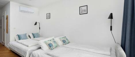 A bedroom with two beds, a hanging light fixture, and a wall-mounted air conditioner.