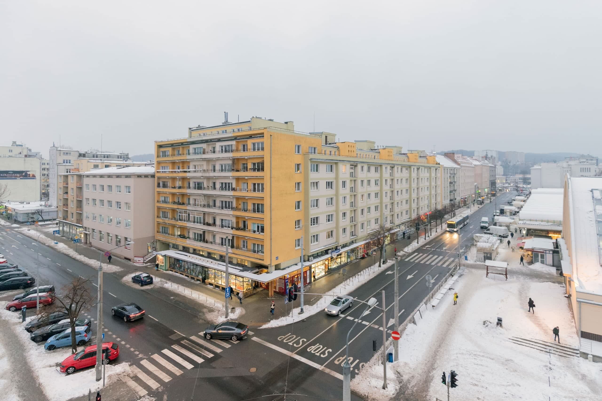 A multi-story building with a yellow facade, located at a city intersection.