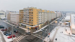 A multi-story building with a yellow facade, located at a city intersection.