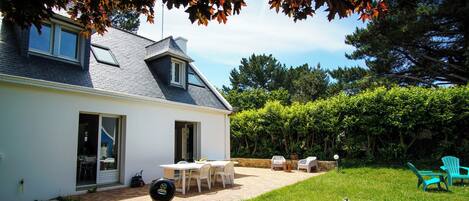 A house with a patio, outdoor seating, and a grill.