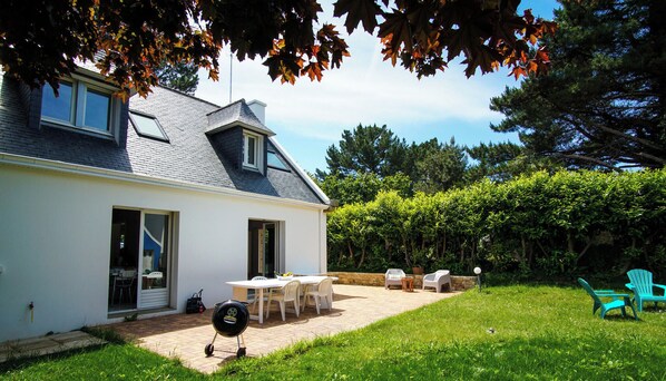 Une maison dotée d’un patio, d’un espace salon extérieur et d’un barbecue.